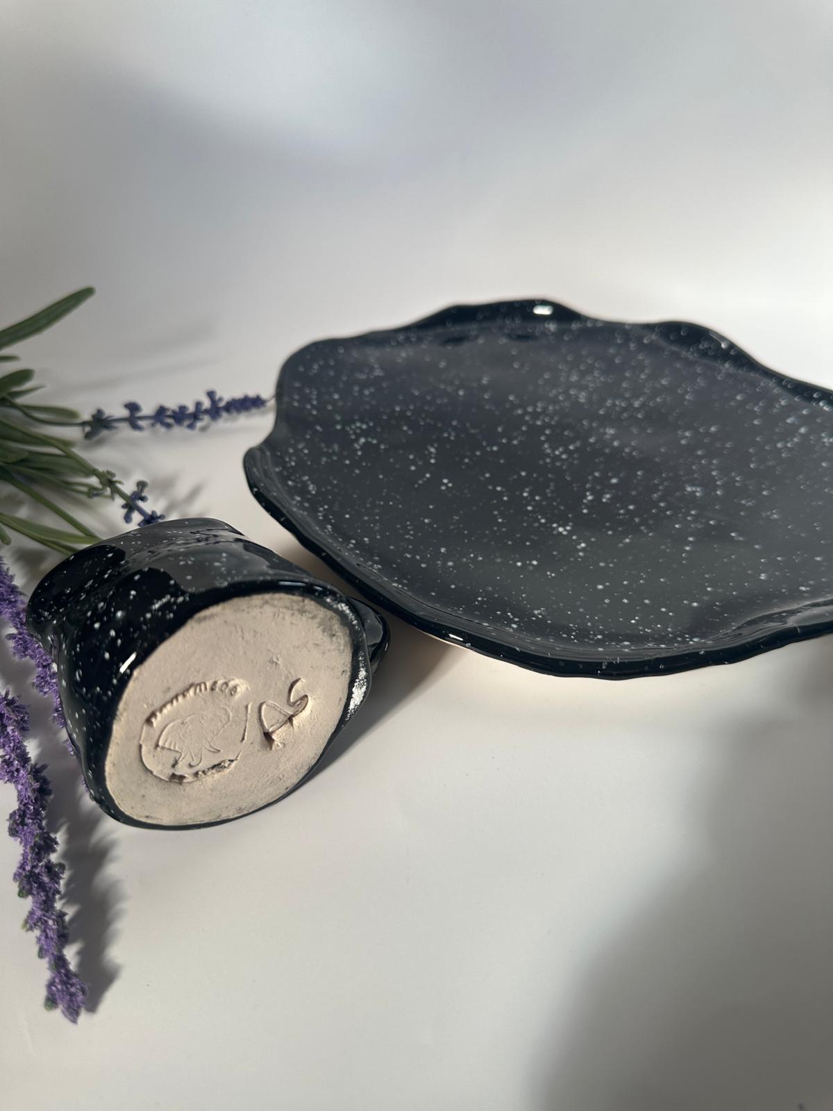 Teller mit Krug, handgemacht, glasiert in schwarz mit weißen Sprenkeln.